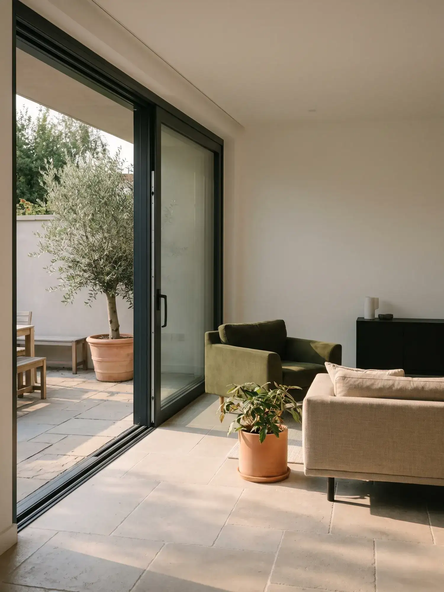 Baie vitrée coulissante en aluminium à profilés fins ouvrant un séjour sur une terrasse